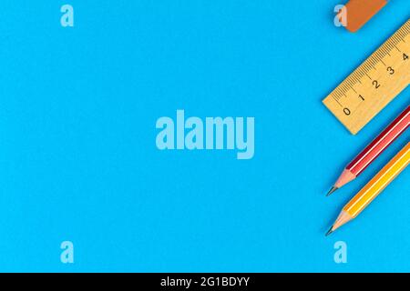 School stationery with lead pencils and wooden ruler, border composition, flat lay background, blue desktop with copy space, top view Stock Photo