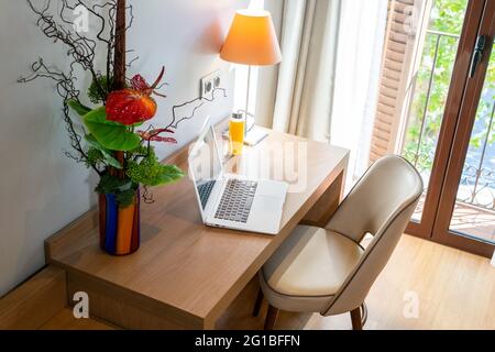 From above of table with netbook placed near bunch of plants and bottle of juice in stylish apartment Stock Photo