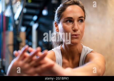 Fit female athlete in sportswear doing exercise in gym looking away Stock Photo