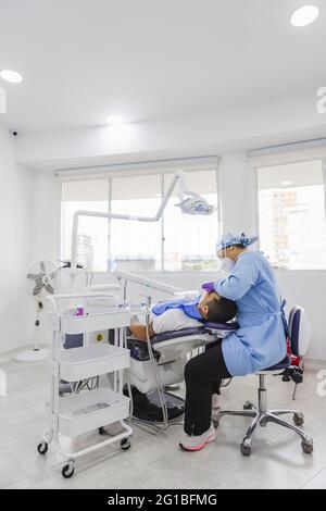 Side view of female patient with retractor in mouth lying on dental ...