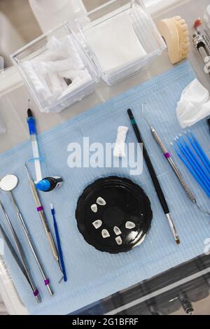 From above of jar with teeth between assorted orthodontic tools on napkin against jaw cast in hospital Stock Photo