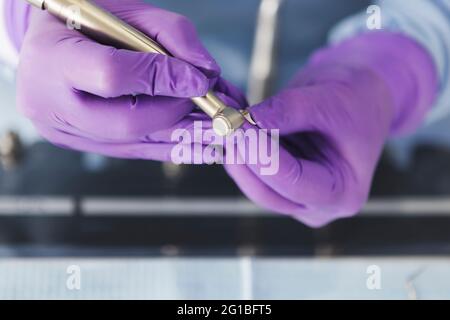 Crop dentist in gloves working with drilling machine in dental clinic Stock Photo