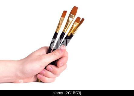 The artist's hand holds the paint brushes on a white background.Copy space. Close-up. Stock Photo