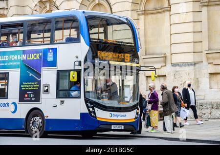 A bus stops outside University of Oxford, Queen's College on the High Street in Oxford, UK. Stock Photo