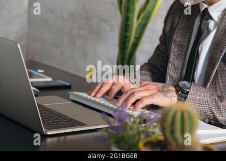 Cropped unrecognizable middle aged male entrepreneur in formal wear working on laptop at table in the office Stock Photo