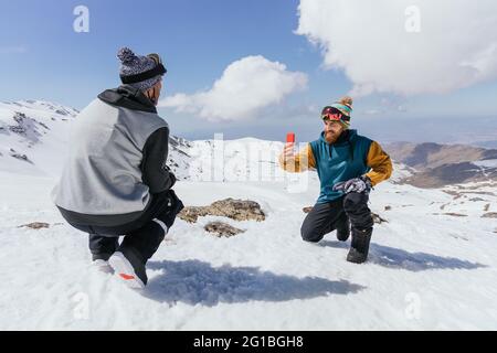 Content male friends in sports clothes taking a photo on cellphone against Sierra Nevada in wintertime Stock Photo