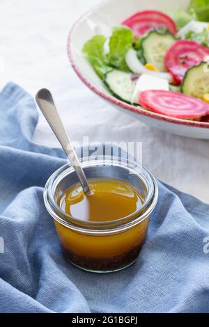 High angle spoon in glass bowl with honey placed on table next to vegetarian salad with cucumber and beetroot with green leaves and corn Stock Photo