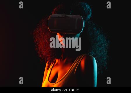 Anonymous ethnic female exploring virtual reality in headset on black background Stock Photo