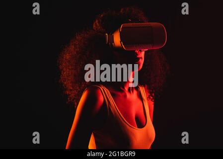 Anonymous ethnic female exploring virtual reality in headset on black background Stock Photo