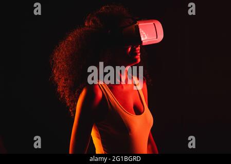 Anonymous ethnic female exploring virtual reality in headset on black background Stock Photo