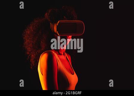 Anonymous ethnic female exploring virtual reality in headset on black background Stock Photo