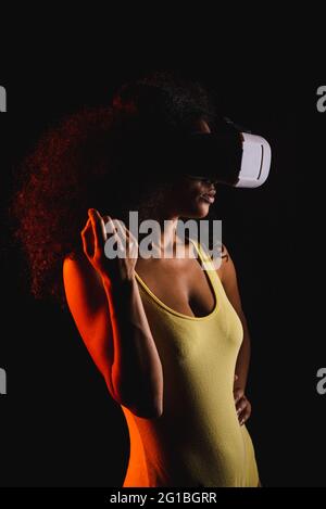 Anonymous ethnic female exploring virtual reality in headset on black background Stock Photo