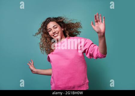 Positive young female jumping smiling looking at camera against blue background Stock Photo
