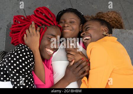 High angle of African American female best friends lying together and embracing each other while having fun Stock Photo