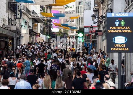 Madrid, Spain. 06th June, 2021. Crowds wearing face masks to stop the spread of coronavirus (COVID-19) walk in Preciados Street, a shopping area near Sol Square in downtown Madrid. A sign reminds the mandatory use of face masks and the need to maintain social distance. Credit: Marcos del Mazo/Alamy Live News Stock Photo