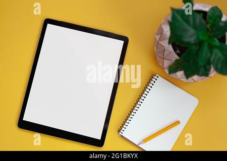 Tablet screen mockup and notepad isolated on yellow background, top view Stock Photo