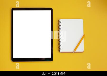 Tablet screen mockup and notepad isolated on yellow background, top view Stock Photo