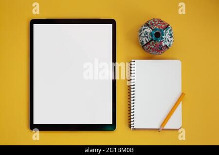 Tablet screen mockup and notepad isolated on yellow background, top view Stock Photo
