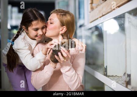 Mother with her daughter holding rabbit together at pet store Stock Photo