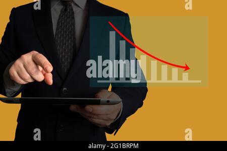 Businessman pointing at a chart on his tablet. Chart illustrating decreasing cost, downtimes, levels of waste, customer dissatisfaction. Stock Photo