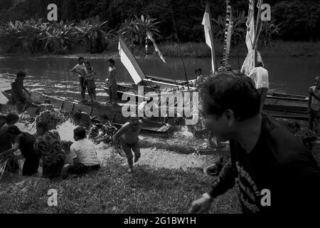 Sungai Uluk Palin, Kapuas Hulu, West Kalimantan, Indonesia. March 2007. People splashing water at each others as a purifying act, as a boat carrying the family of the new traditional leader of Dayak Tamambaloh longhouse community arrives, after a visit to a nearby cemetery where the former chief is buried. This is a part of a series of traditional events held to honour the former traditional chief, who passed away several weeks earlier.--Photographed on black and white film, scanned, digitalized. Stock Photo