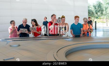 Cupertino, CA, USA - August 2019: Apple Store Cupertino with people looking at Infinite Loop Apple Headquarters through virtual reality using iPad tab Stock Photo
