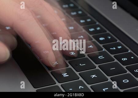 fingers typing on a computer keyboard using a long exposure ghosting technique to simulate motion in photography Stock Photo