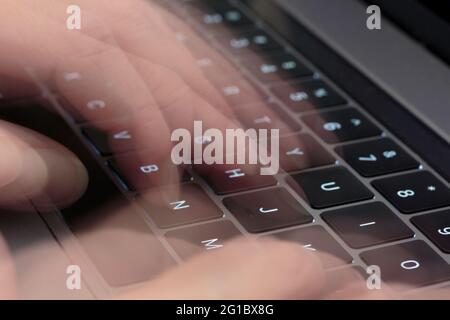 fingers typing on a computer keyboard using a long exposure ghosting technique to simulate motion in photography Stock Photo