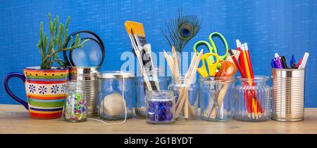 Recycled jars, tin and mug reused for different contents on wooden bench,  recycling at home for sustainable living, save money and zero waste Stock Photo