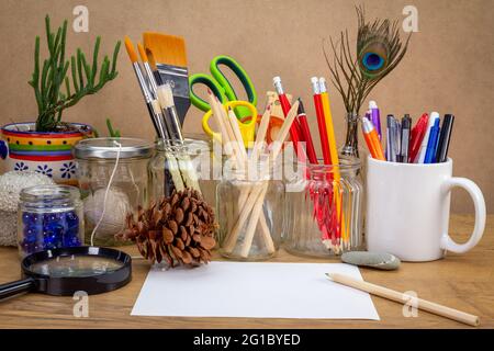 Recycled jars, tin and mug reused for different contents on wooden bench,  with blank note paper room for text, reuse for sustainable living, save mon Stock Photo