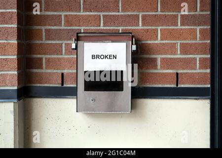 Broken building enterphone or intercom. Paper notice stating "broken" is taped over the number pad. Autodialer interphone system mounted on brick wall Stock Photo