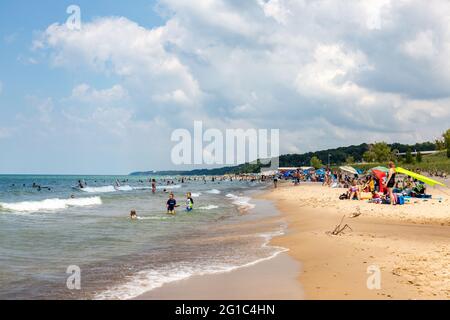 Sunbathers, swimmers and beachcombers enjoy a hot summer day at a sandy Lake Michigan beach in Warren Dunes State Park near Sawyer, Mich., USA. Stock Photo