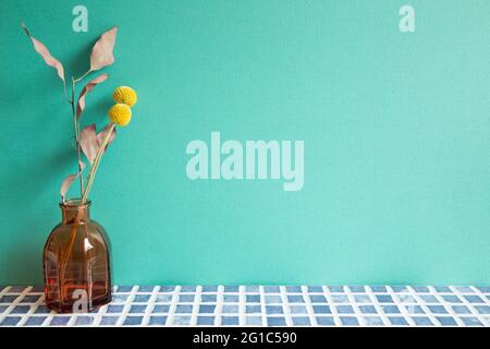 Vase of dry flowers on blue ceramic mosaic tile table. mint wall background. Home interior Stock Photo