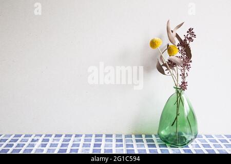 Vase of dry flowers on blue ceramic mosaic tile table. white wall background. Home interior Stock Photo