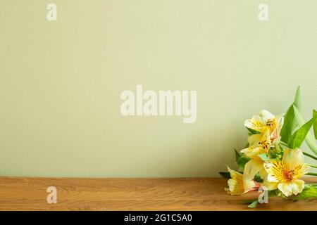 Yellow alstroemeria flowers on wooden table. khaki green background Stock Photo