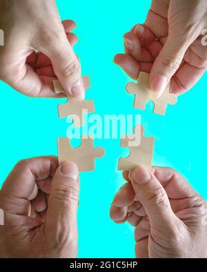 Business people assembling jigzaw puzzle. Close up shot. Concept of cooperation, teamwork and support. Top view. Stock Photo