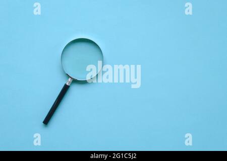 Magnifying glass on blue background. Copy space. Top view. Stock Photo