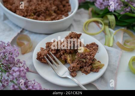 sweet home made chocolate rhubarb crumble with lilach flowers Stock Photo