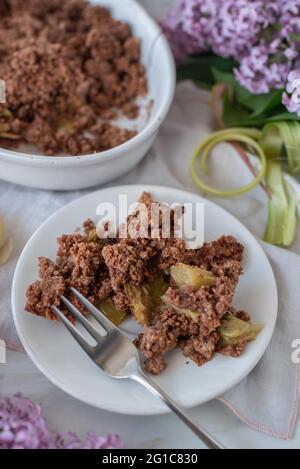sweet home made chocolate rhubarb crumble with lilach flowers Stock Photo