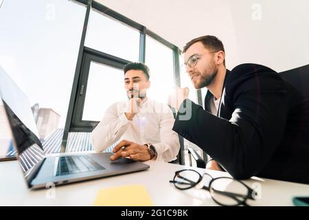 Two employees of software development company are working on startup using laptop Stock Photo
