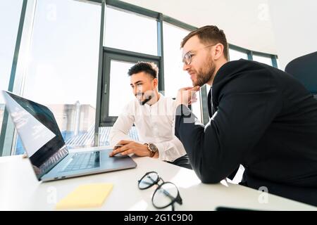 Two office employees work at laptop in spacious office with panoramic windows Stock Photo