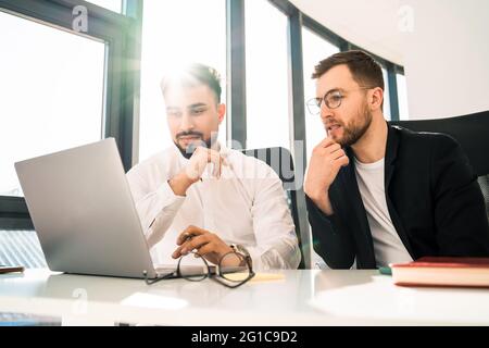 Two handsome businessmen work together on laptop Stock Photo