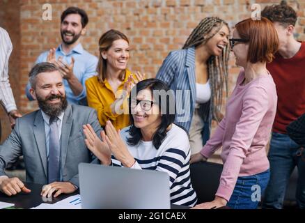 Group of entrepreneurs architects laughing indoors in office, working on project. Stock Photo