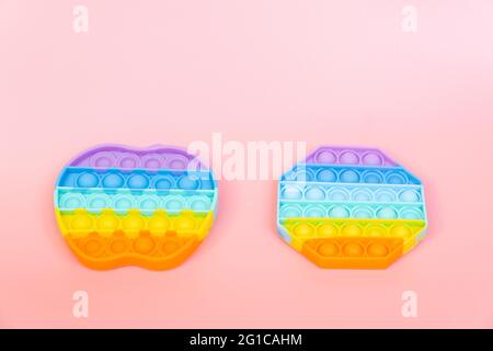 colorful silicone antistress sensory toy fidget push pop it on pink background Stock Photo