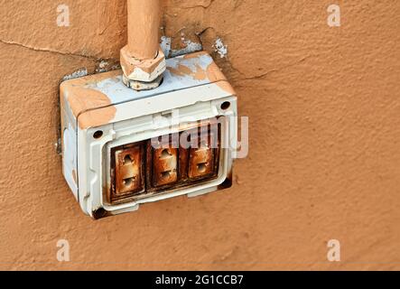 The dangerous old electric plug on the wall Stock Photo