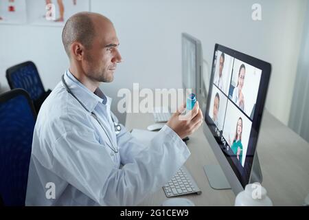 Chef doctor discussing new vaccine against coronavirus with colleagues from other hospitals during online meeting Stock Photo