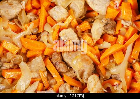 Meat with vegetables in the cauldron. Pork chunks mixed with onions and carrots. Cooking pilaf. Home cooking concept. Stock Photo