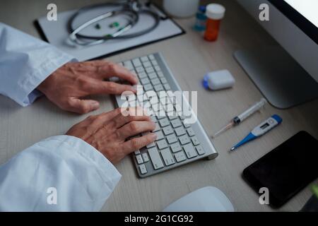 Hands of physician working on computer after making rounds and examining patients in the morning Stock Photo