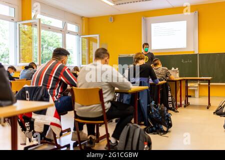 07 June 2021, Baden-Wuerttemberg, Heitersheim: Pupils sit in class on Monday morning while a teacher stands in front of the blackboard next to open windows. They are all back at St John's Secondary School for the first day of school after the Whitsun holidays. After nearly half a year of home schooling, hundreds of thousands of students in the Southwest can return to the classroom. The reason is the falling incidence of corona and the vaccination of almost all teachers. Photo: Philipp von Ditfurth/dpa - ATTENTION: Only for editorial use in connection with a report on the reopening of the schoo Stock Photo