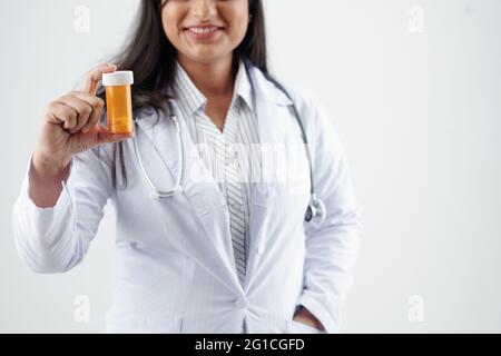 Smiling female general practitioner holding plastics bottle with pills or supplements Stock Photo